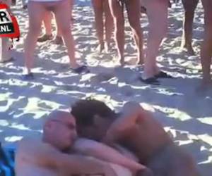 Sex trio op het strand met een kring van voyeurs